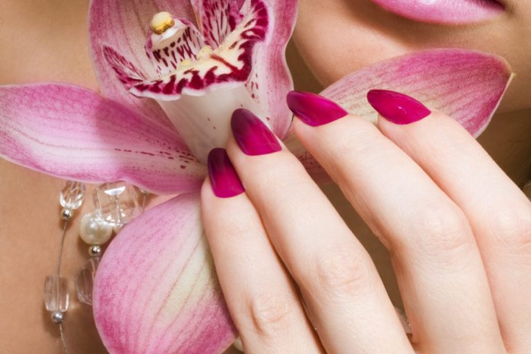 Polished fingers holding a flower